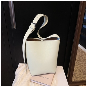 Détail du sac seau minimaliste en cuir crème avec bandoulière réglable et boucle