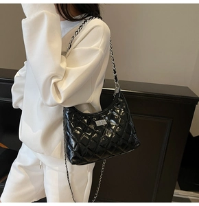 Detail of glossy black quilted hobo bag featuring silver metal chain and twist lock