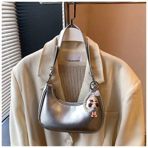 Detail of silver metallic crescent bag with pearl chain and charm on a blazer