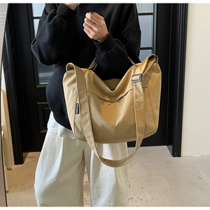 Detail of adjustable wide shoulder strap and side zipper pocket on khaki canvas tote bag