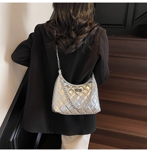 Silver quilted crescent bag with metallic chain and turn-lock shown on a model