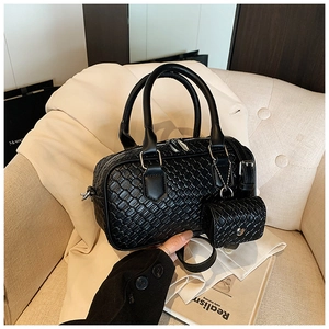 Close-up of black woven texture bowling bag with mini coin purse on a beige sofa
