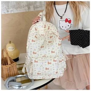Detail of cream backpack with cartoon dog patterns showing drawstring and handle