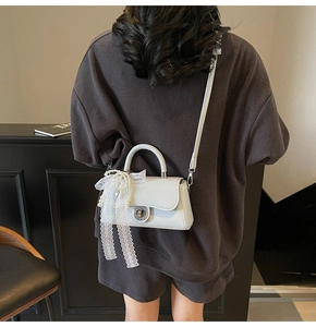 Rear view of a light blue-grey crossbody bag with lace ribbon and bead pendant decor