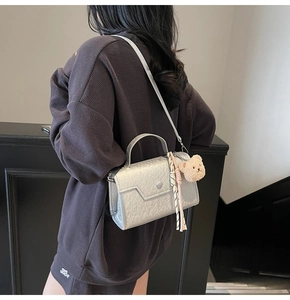 Silver metallic crossbody bag featuring a plush bear charm and woven tassel detail