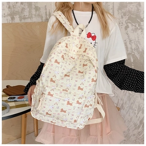 Detail view of cream canvas backpack featuring cute cartoon dog prints and pink bows