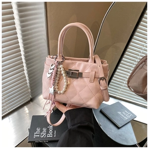 Détail du sac matelassé rose avec charms en perles et fermoir rotatif en métal argenté