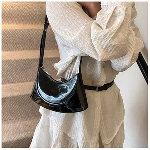 Detail of black patent leather dumpling bag with white NO FILTER print and silver zipper