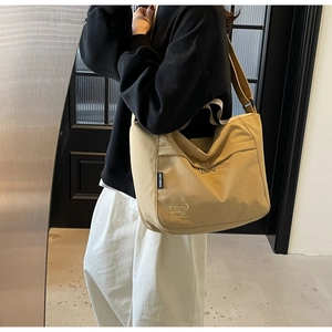 Detail of khaki canvas tote featuring delicate dog embroidery and adjustable wide strap
