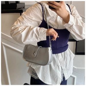 Close-up of metallic silver shoulder bag with buckle detail on white shirt outfit