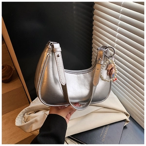Detail of silver metallic dumpling bag with pearl cartoon charm and zipper closure