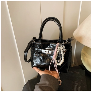 Détail du sac matelassé noir brillant avec fermoir en métal argenté et breloques en perles