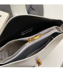 Close-up of white oil wax leather handbag showing golden zipper and dark fabric lining