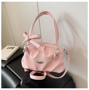 Gros plan du sac à main en cuir rose avec nœud décoratif et fermoir métallique
