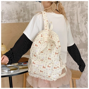 Detailed close-up of a cream canvas backpack with cute puppy prints and adjustable straps