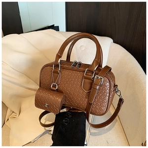 Detail of brown woven texture Boston bag with mini pouch on a beige fabric sofa