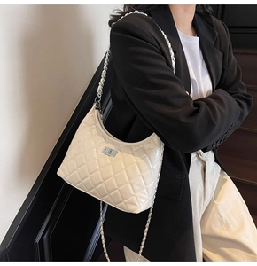 Close-up of white quilted patent leather texture with silver chain and metal lock