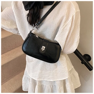 Close-up of black shoulder bag with glossy crinkled texture and silver metal buckle detail