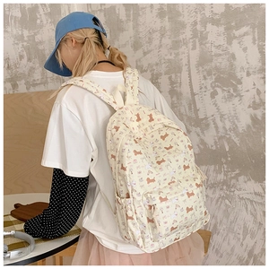 Detail of cream canvas backpack featuring brown cartoon dachshund dog prints and side pockets
