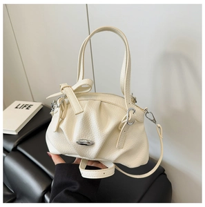 Détail du sac à main plissé crème avec nœud décoratif et boucle en métal argenté
