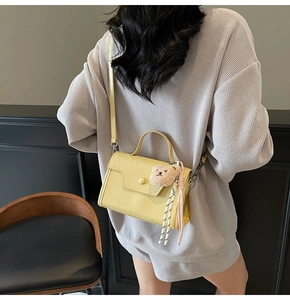 Detail showing light yellow faux leather square bag with cute bear charm and silk ribbon