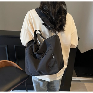 Detailed view of black nylon tote bag with wide adjustable strap worn by a model