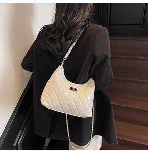 Close-up of cream quilted crossbody bag with silver twist lock and chain strap