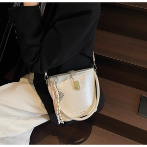 Vue détaillée du sac seau crème avec fermoir rotatif doré et texture en cuir grainé