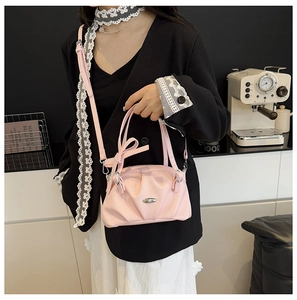 Détails du sac à main en cuir froncé rose avec nœud décoratif et emblème argenté