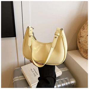 Detail of pale yellow half-moon underarm bag with smooth leather and silver hardware