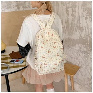 Detail of beige canvas backpack with brown cartoon dog prints and front zipper pocket