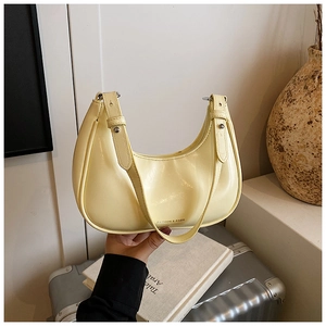 Detail of yellow crescent shoulder bag in shiny PU leather with gold fashion lettering