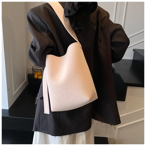 Seitenansicht der cremefarbenen Beuteltasche mit breitem Riemen und Lederdetails