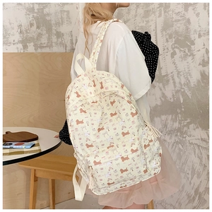 Girl wearing cream backpack with sausage dog pattern in a cozy lifestyle setting