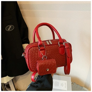 Detail of red bowling handbag with textured weave pattern and matching mini charm pouch