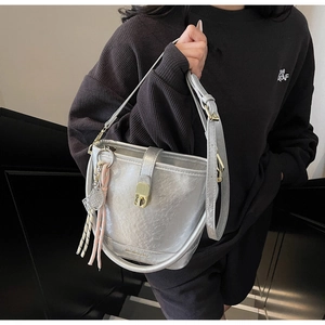 Détail d'un sac seau argenté plissé avec fermoir doré et pendentif raquette de tennis