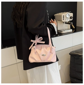 Sac à bandoulière rose en cuir synthétique plissé avec détail de nœud porté par mannequin