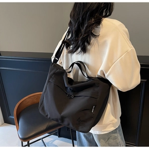 Detail of black large capacity nylon tote bag featuring cartoon embroidery and adjustable strap