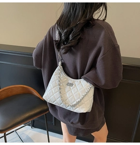 Detail view of white quilted chain bag with silver buckle and metallic strap