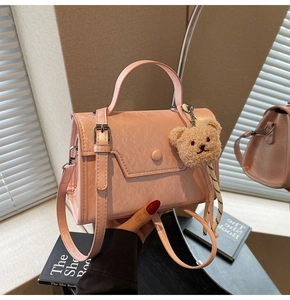 Detail of light pink crossbody bag with pleated texture and plush bear charm