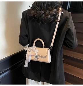Detail of beige crossbody bag with lace bow, pearl pendant and silver twist lock