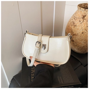 Minimalist cream white shoulder bag on black art book with silver hardware detail