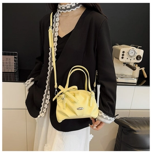 Sac à main chic jaune citron avec nœud et logo porté par un mannequin dans un café