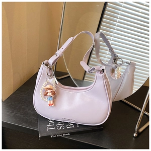 Close-up of light purple dumpling bag with cartoon doll pendant and pearl strap detail