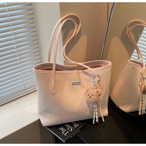 Dettaglio borsa tote rosa con trama intrecciata e ciondolo a forma di orsetto peluche