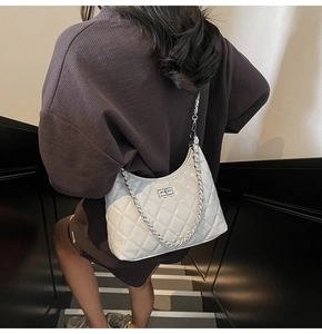 Close-up of a white quilted crossbody bag with silver clasp and metal chain strap