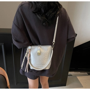 Détail du sac seau argenté montrant la texture métallique, fermoir doré et gland