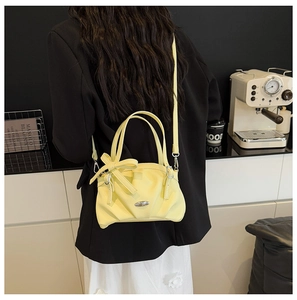 Détail d'un sac à main jaune vif avec une grande décoration en nœud et plaque en métal