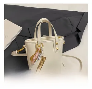 Detail of a creamy leather bucket bag with decorative woven strap and golden abacus charm