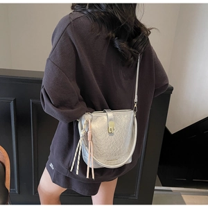 Détail du sac seau métallisé argenté avec fermoir doré et longues franges sur la bandoulière